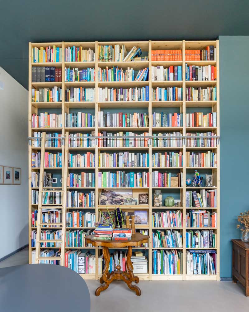 houten boekenkast met ladder tot aan het plafond