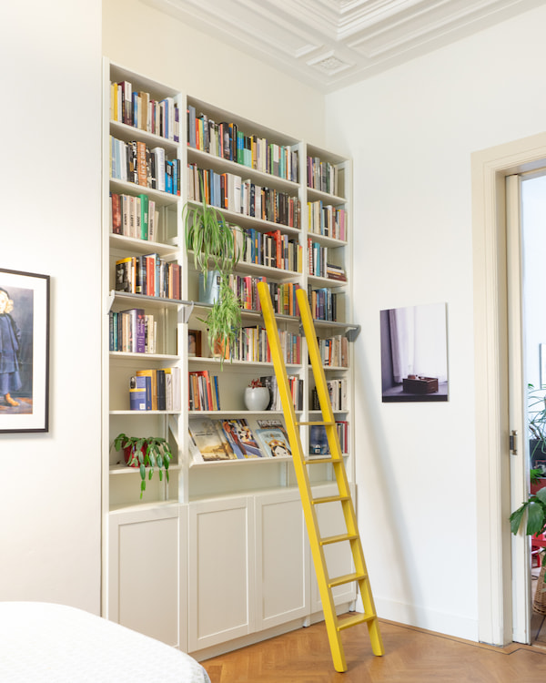 hoge witte boekenkast met gele ladder